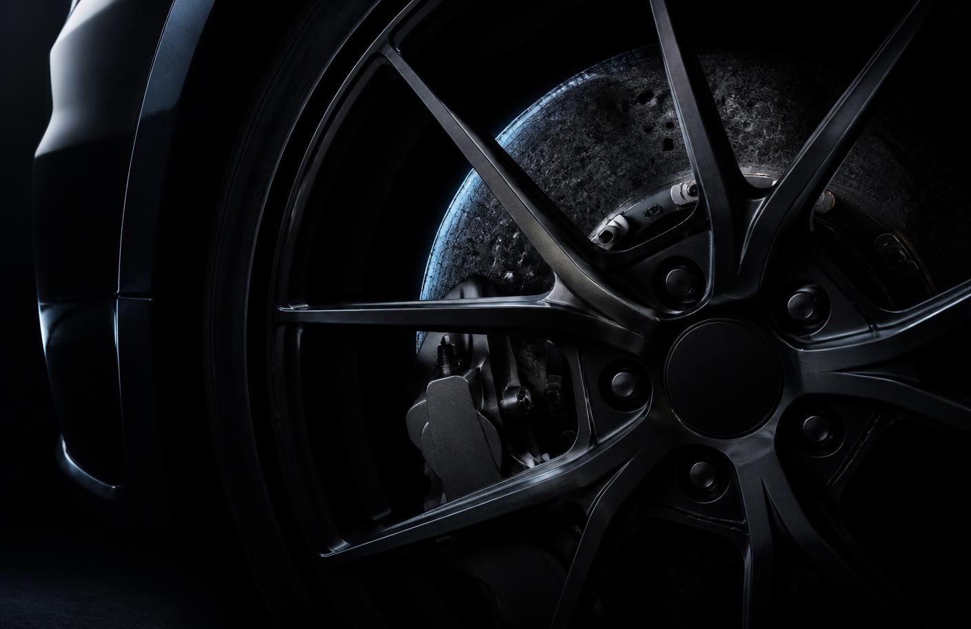 Forged wheel and carbon ceramic brake detail on a dark performance car